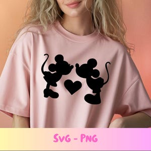 May include: A light pink t-shirt featuring a black silhouette design of two cartoon mice facing each other, with a heart between them. The text "SVG - PNG" is at the bottom of the shirt.