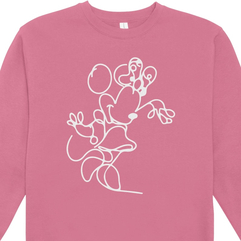 May include: A pink sweatshirt featuring a white line drawing of a cartoon character. The design is a continuous line, depicting the character's head, ears, and body. The sweatshirt has a crew neck and long sleeves.
