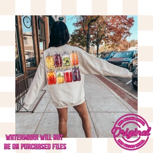 May include: A white sweatshirt with a graphic of six mason jars filled with different fruits and the text "Homegrown" in gold lettering.