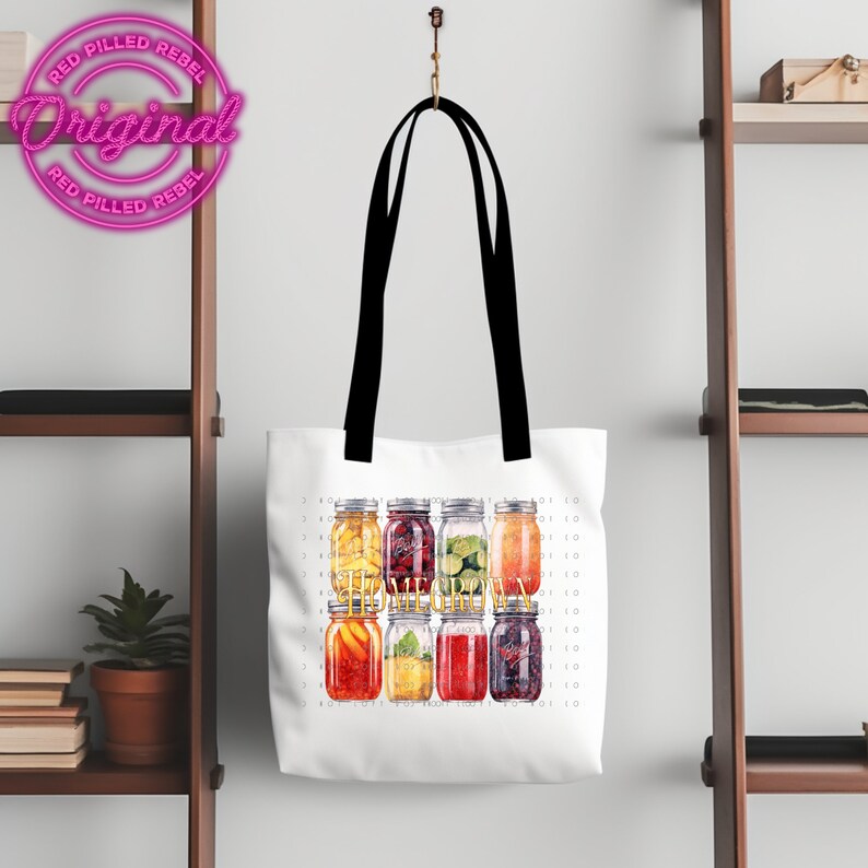 May include: White tote bag with black straps featuring a graphic of six mason jars filled with various fruits and the text "The Melanin" in gold lettering.