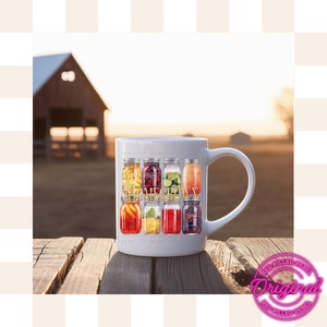 May include: White ceramic mug with a design of jars filled with various fruits and the text "Homegrown". The mug is sitting on a wooden table with a blurred background of a red barn and a sunset.