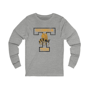 May include: A long-sleeve gray shirt featuring a yellow and black bee design. The shirt has the words "GEORGIA TECH" in a black outlined font. The bee is centered between the words.