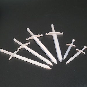 May include: Six silver-colored toy swords of varying sizes, arranged in a fan shape on a black background.