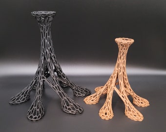 May include: Two decorative candle holders made of a black and brown lattice design. The larger holder is black and the smaller holder is brown.