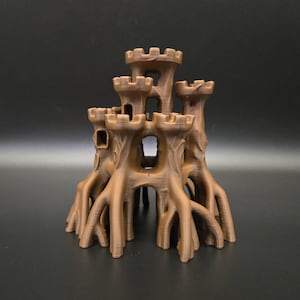 Op de afbeelding: Een bruin, 3D-geprint kasteelmodel met meerdere torens en een gedetailleerde, boomachtige basis. Het kasteel heeft open ramen en een gestructureerd oppervlak, waardoor een decoratief stuk met fantasiethema ontstaat.