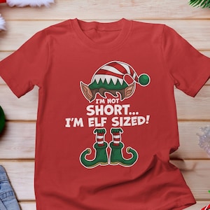 May include: Red t-shirt with a green elf illustration and the text "I'm not short... I'm elf sized!"