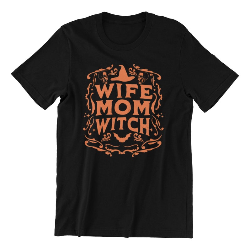 Pu&ograve; includere: Maglietta nera con un design grafico arancione che dice "Wife Mom Witch" con un cappello da strega e teschi.