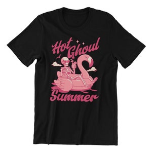 Może przedstawiać: Czarny T-shirt z r&oacute;żowym nadrukiem przedstawiającym szkielet na dmuchanym flamingu. Tekst "Hot Ghoul Summer" jest nadrukowany na r&oacute;żowo.
