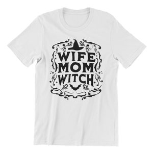 Pu&ograve; includere: Maglietta bianca con un design grafico nero che dice "Wife Mom Witch" con un cappello da strega e pipistrelli.