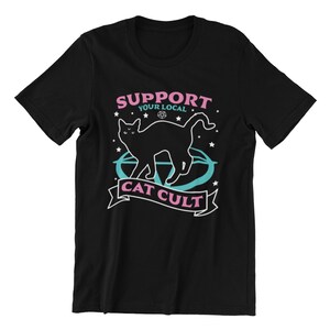 May include: Black t-shirt with a graphic of a black cat standing in a pentagram with the text "Support Your Local Cat Cult" in pink and blue.