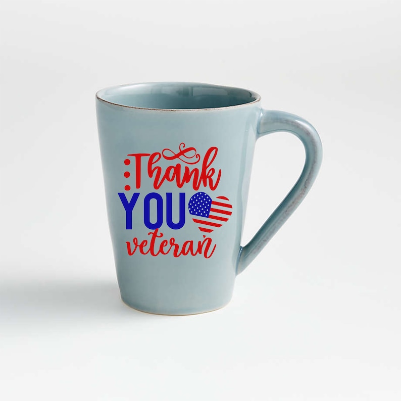 Peut inclure: Une tasse en c&eacute;ramique bleu clair avec une anse incurv&eacute;e. La tasse porte l'inscription "Thank You Veteran" en rouge et bleu, avec un motif de c&oelig;ur drapeau am&eacute;ricain. La tasse est de taille standard.