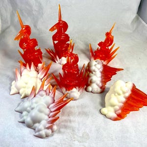 May include: A collection of seven plastic action figure effect pieces designed to simulate explosions and fire. The set includes translucent orange flame spirals and opaque white cloud-like bases with pointed orange tips, creating dynamic energy.