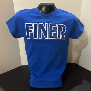 May include: A royal blue t-shirt with the word "FINER" printed in white with a blue outline.