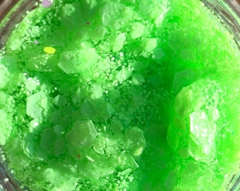 May include: A clear glass jar filled with green glitter. The glitter is a mix of fine and chunky pieces.