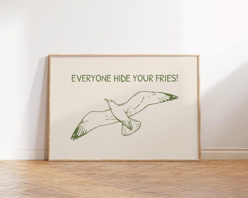 Pode incluir: Uma impress&atilde;o emoldurada com uma ilustra&ccedil;&atilde;o verde de uma gaivota em voo. O texto "EVERYONE HIDE YOUR FRIES!" est&aacute; impresso acima. O fundo &eacute; bege claro e a moldura &eacute; de madeira clara.