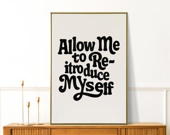 May include: A framed art print with the text "Allow Me to Re-introduce Myself" in bold, black lettering. The print is displayed on a wooden cabinet with gold candle holders. The artwork has a retro, vintage aesthetic.
