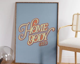May include: A framed print with a blue background and the text "Home Body Club" in a retro font with orange and yellow colors.