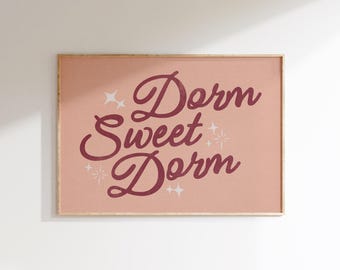May include: A pink framed print with the text "Dorm Sweet Dorm" in a burgundy script font. The text is surrounded by small white stars.