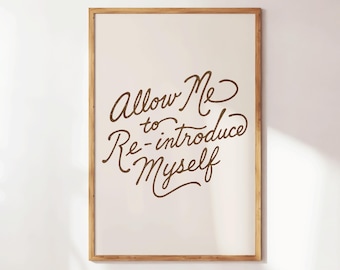 May include: A framed print with the text "Allow Me to Re-introduce Myself" in a brown, cursive font. The print has a cream-colored background and a natural wood frame, suitable for home decor.