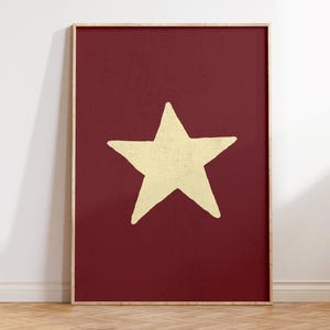 Pu&ograve; includere: Una stampa incorniciata con una grande stella gialla disegnata a mano su uno sfondo rosso scuro.