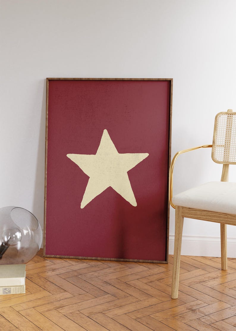 Pu&ograve; includere: Una stampa incorniciata con una grande stella color crema su uno sfondo rosso scuro.