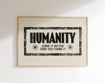 May include: A framed print with the word "HUMANITY" in bold black letters. Below, the text reads "LEAVE IT BETTER THAN YOU FOUND IT." The design is set against a cream background with a decorative black border and sunburst details.