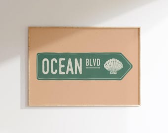 May include: A tan-coloured framed print with a green and white sign that reads "Ocean Blvd" with a seashell graphic.