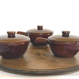 May include: A set of three ceramic mugs with a speckled, matte finish. The mugs are in shades of cream, light gray, and dark gray. Each mug has a simple, minimalist design and a rounded handle.