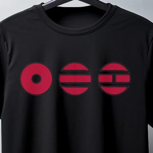 Op de afbeelding: Zwart T-shirt met ronde hals met drie rode cirkelvormige ontwerpen. De eerste cirkel is effen, de tweede heeft horizontale strepen en de derde heeft een kruis. De tekst "mockup for inspiration" staat onderaan.