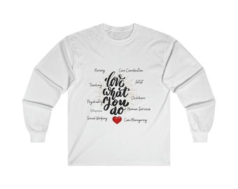 May include: White long-sleeve t-shirt with a black graphic that says "love what you do" with a red heart. The graphic is surrounded by a circle of words including "nursing", "teaching", "psychiatry", "entrepreneur", "social working", "care coordination", "artist", "childcare", "human services", and "case managing".
