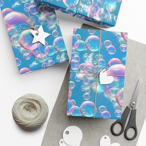 Peut inclure: Des boîtes cadeaux enveloppées dans du papier bleu avec un motif de bulles, attachées avec de la ficelle et ornées d'étiquettes en forme d'étoile et de cœur. Une pelote de ficelle, des ciseaux et des étiquettes vierges sont également visibles.