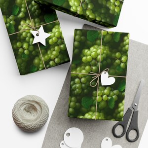 May include: Three gift boxes wrapped in green and white patterned paper with green grapes and leaves. The boxes are tied with twine and decorated with white paper stars and hearts.