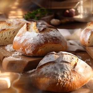 Könnte beinhalten: Vier frisch gebackene Brote, mit Mehl bestäubt, auf einer Holzoberfläche. Das Brot ist weich und fluffig, mit einer goldbraunen Kruste.