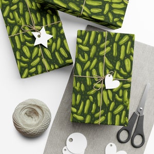 May include: Three green gift boxes with a pattern of green cucumbers on a dark green background. The boxes are tied with twine and have white gift tags attached.