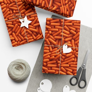 May include: Three gift boxes wrapped in orange and brown patterned paper with a carrot design. The boxes are tied with twine and decorated with white paper stars and hearts.