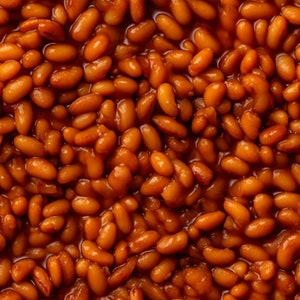 Puede incluir: Una imagen de primer plano de un tazón de frijoles horneados marrones. Los frijoles están cubiertos con una salsa espesa y marrón.