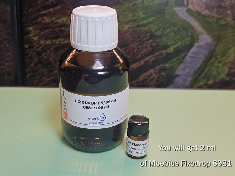 May include: Two bottles of Fixodrop ES/BS-10, one large and one small. The larger bottle has a white cap and a label with the text "FIXODROP ES/BS-10 8981/100 ml" and "moebius Swiss Made". The smaller bottle is labeled "Fixodrop 8981".