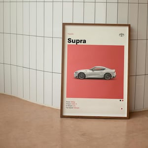 May include: A framed poster with a white Toyota Supra on a red background. The poster has the text "Supra" in a large, bold font and the text "Toyota" in a smaller font. The poster also includes the car's specifications: "Power: 382hp", "Torque: 368lb-ft", "0-60mph: 3.9s", "Top Speed: 155mph".