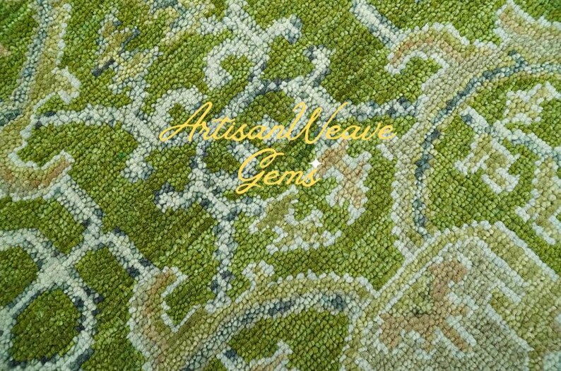 May include: Close-up of a green and white patterned rug with a woven texture. The rug has a subtle floral design and is made of soft, plush fibres. The text "Artisan Weave Gems" is visible in the image.
