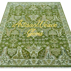May include: A green and cream patterned rug with a fringed edge. The rug has a floral design with a central motif of a tree. The text "Artisan Weave Gems" is visible in the centre of the rug.