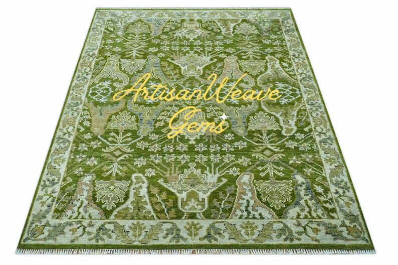 May include: A green and cream patterned rug with a fringed edge. The rug has a floral design with a central motif of a tree. The text "Artisan Weave Gems" is visible in the centre of the rug.
