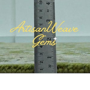 May include: Close-up of a green rug with a ruler measuring 10 cm. The text "Artisan Weave Gems" is visible in the image.