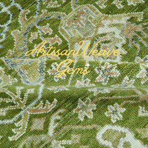 May include: A green rug with a floral pattern. The rug has a light brown and white design. The rug is made of wool and has a soft texture.