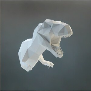 Può includere: Modello di dinosauro T-Rex in carta bianca, con la bocca aperta, che mostra i denti. Il modello è fatto di carta piegata e ha un effetto 3D.