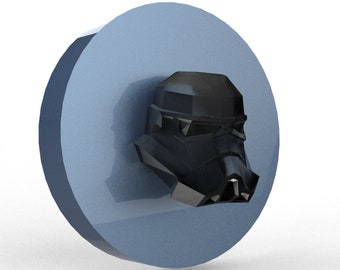 May include: A black Stormtrooper helmet design is featured on a light blue, circular object. The helmet is a prominent, three-dimensional element, with detailed facial features. The object has a glossy finish, suggesting a decorative or collectible item.