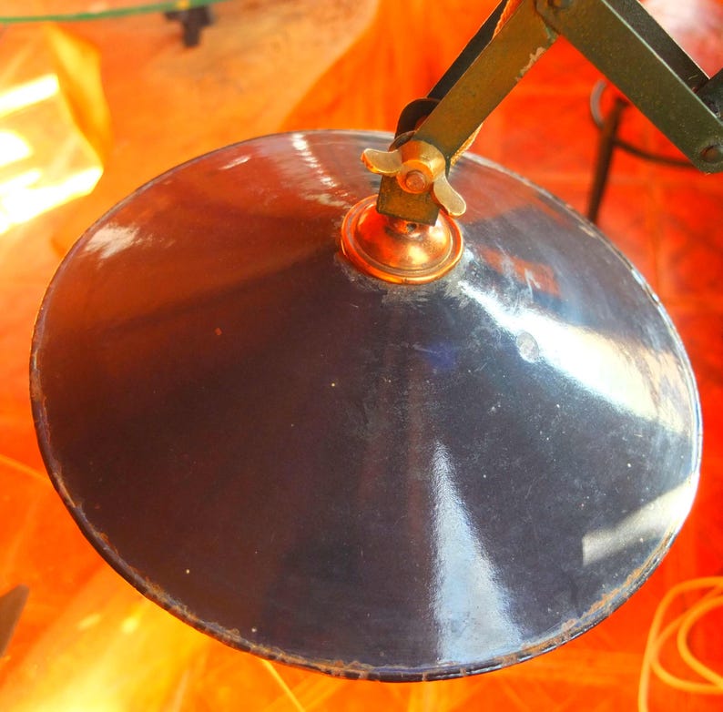 May include: A black metal lampshade with a brass fitting and a decorative knob. The lampshade is round and has a shiny finish.