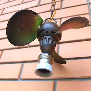 May include: A vintage ceiling fan light fixture with two metal blades and a brass finish. The fan is hanging from a chain with a yellow cord.