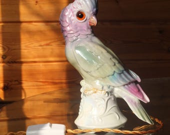 May include: A ceramic parrot lamp with iridescent green, blue, and purple paint. The lamp has a white base with a floral design and a gold cord.