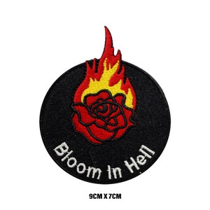 Peut inclure: Patch brodé noir avec une rose rouge en feu et le texte "Bloom in Hell" en blanc. Le patch mesure 9 cm sur 7 cm.