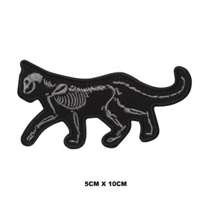 May include: Black iron-on patch of a cat with a visible skeleton, 5cm by 10cm.